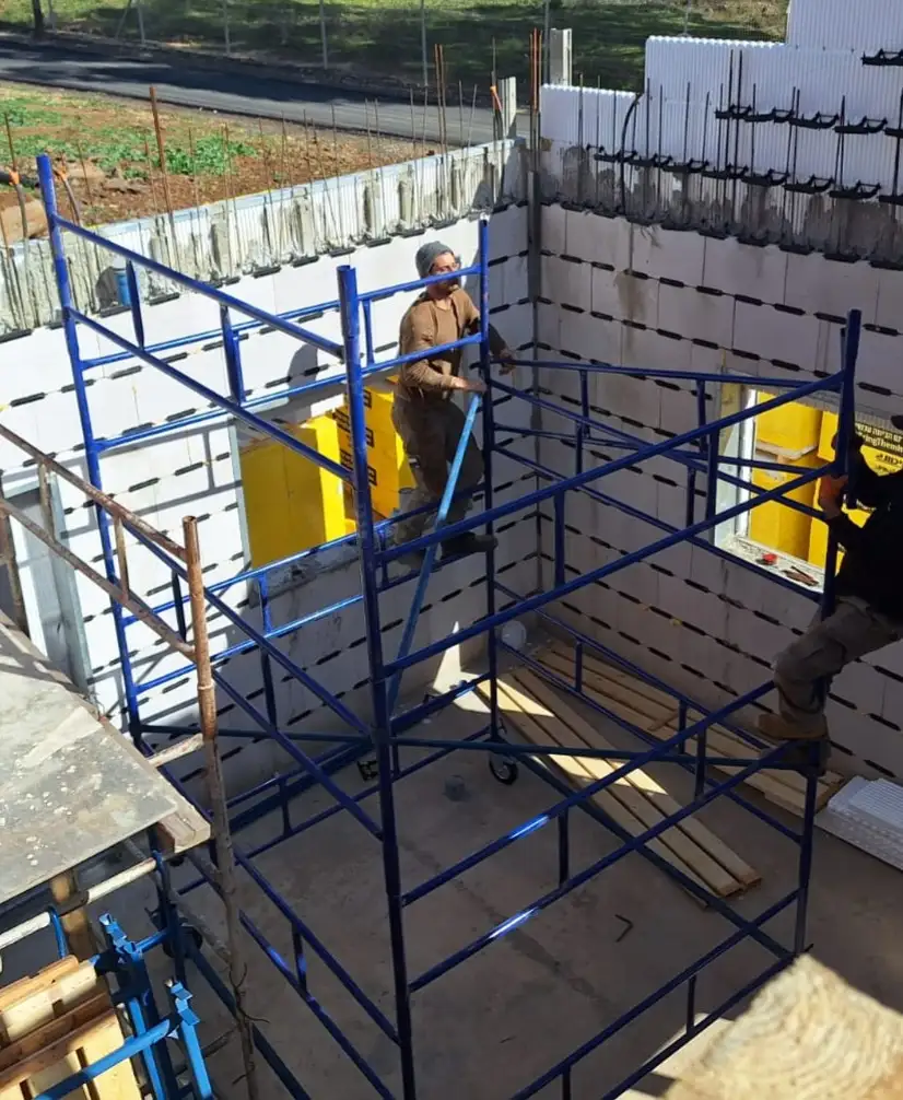 אתר בנייה עם עובדים ופיגומים כחולים.